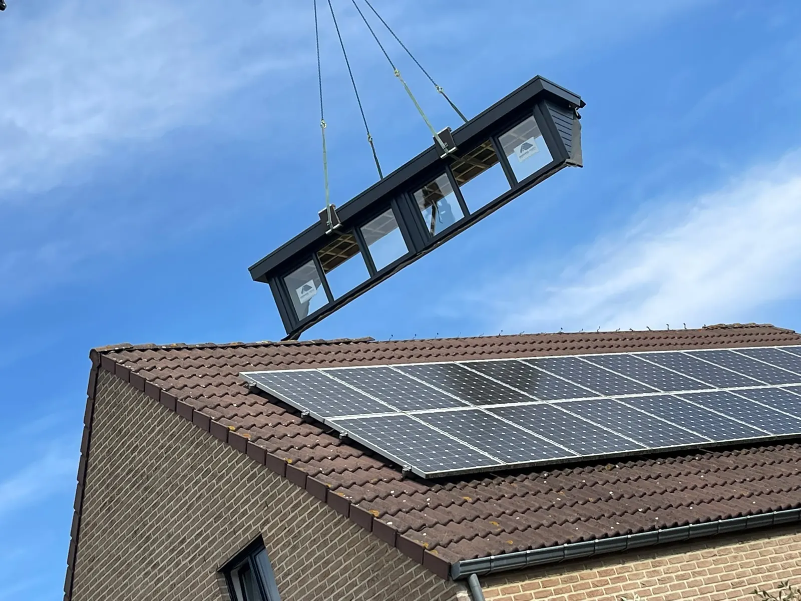 Prefab dakkapel wordt met de kraan naar het dak gehesen